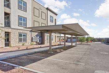 A parking lot in front of a building with a covered walkway.